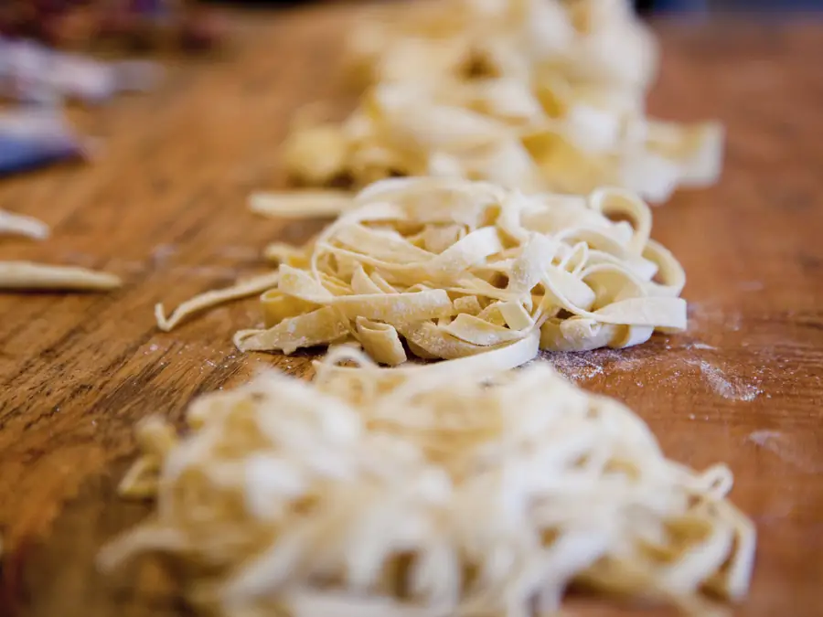 Pasta fresca tirata a mano su tavolo di legno