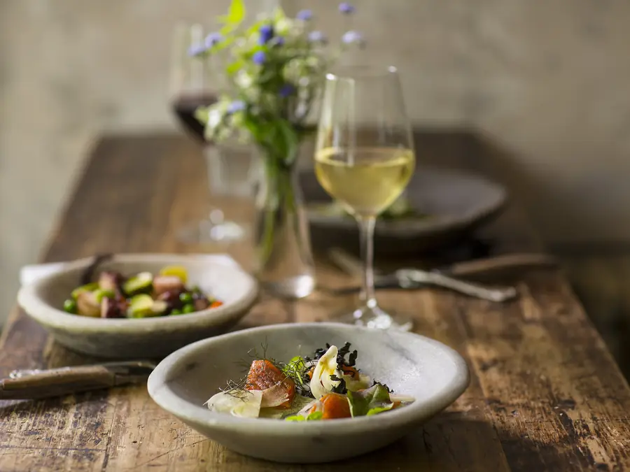 Tavola apparecchiata con vino bianco e piatti