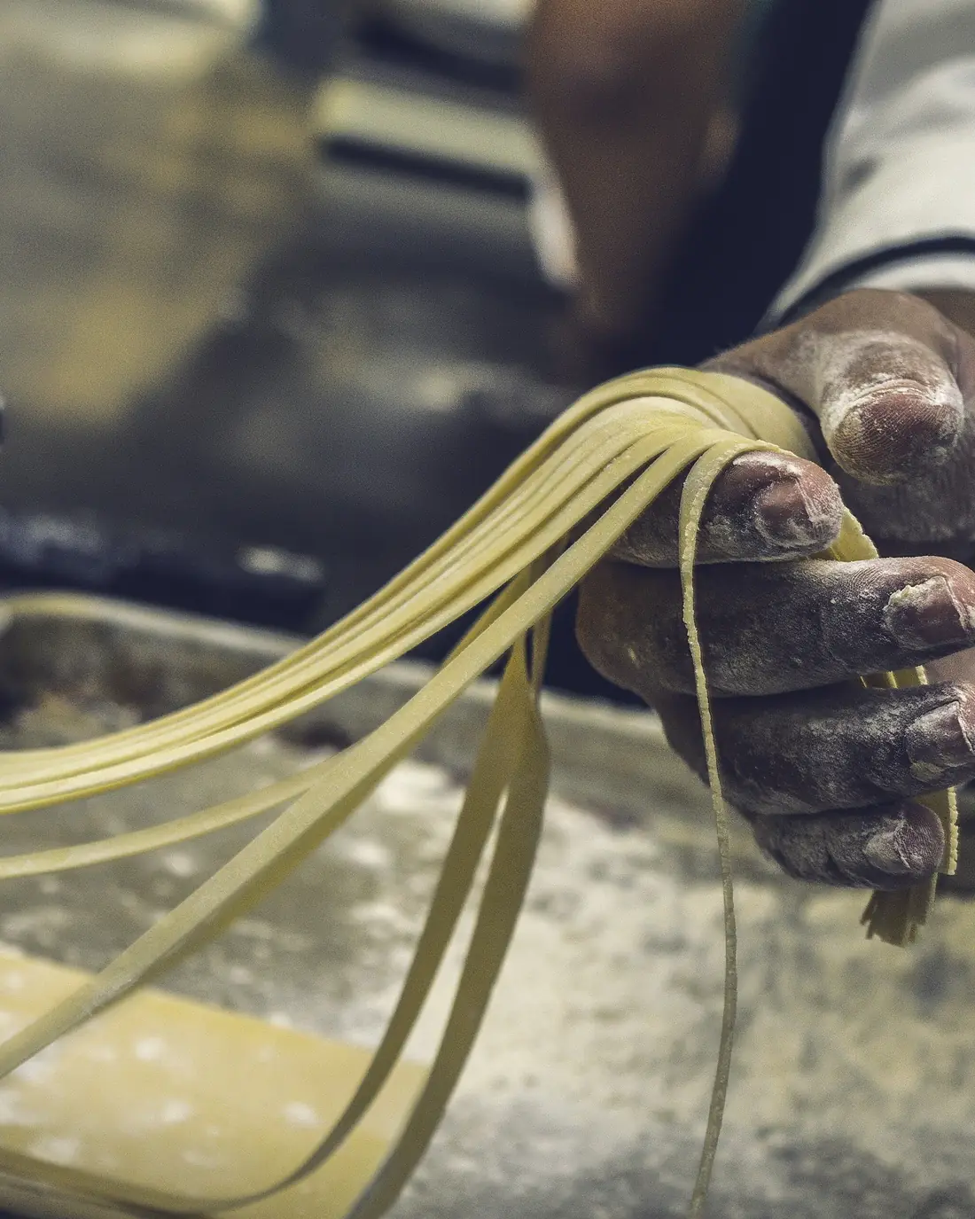 Mani che stendono la pasta fresca